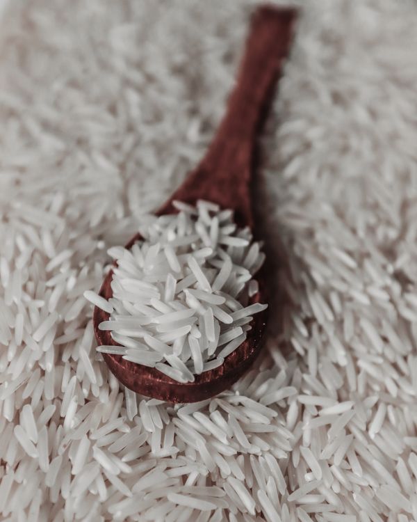 Uncooked rice grains and a wooden spoon